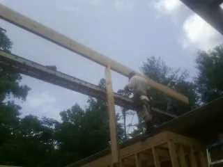 Carpenter setting a ridge beam over a new addition frame — Ice Dam Removal by Roofing Brothers in Glen Burnie