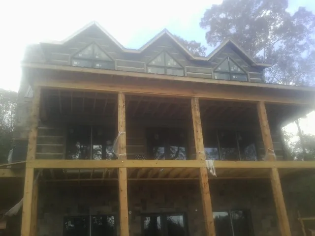 Dormers and porch framing on a large log home under construction — Roof Coating work by our crew in Glen Burnie
