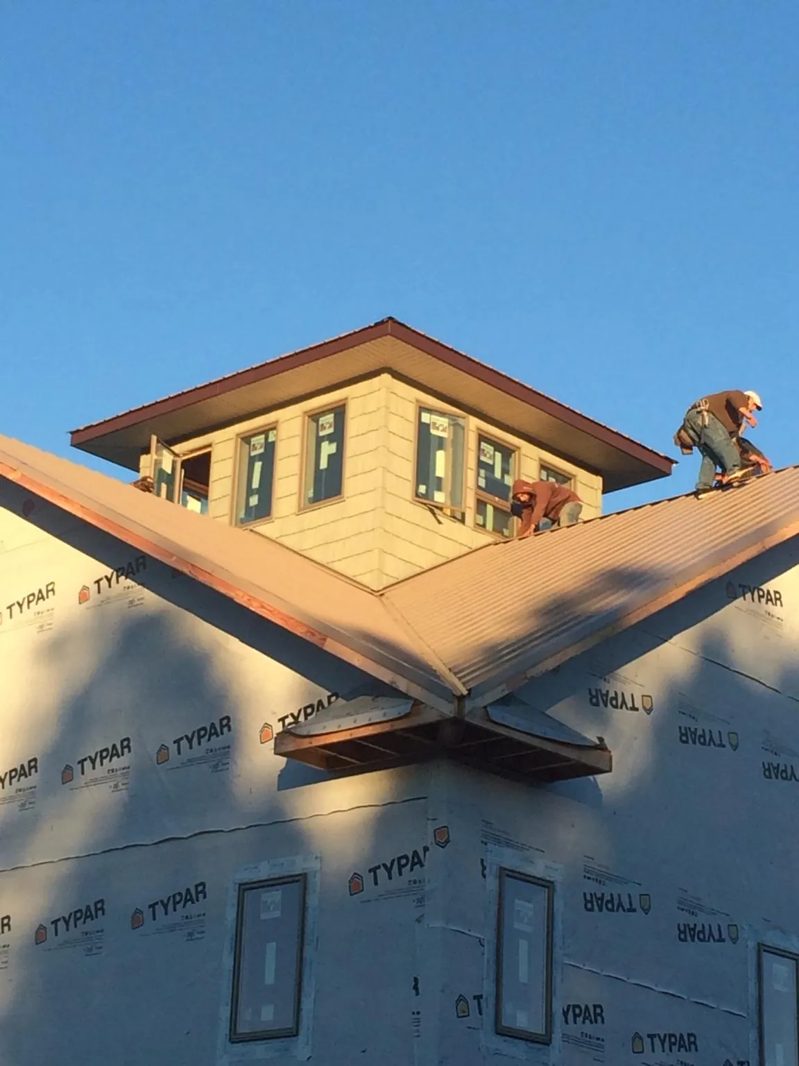 Roofers working around a rooftop cupola on a new metal roof at sunset — Roof Waterproofing in Glen Burnie by Roofing Brothers